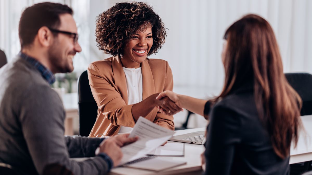 Due persone si stringono la mano durante un colloquio di lavoro in un ufficio luminoso.