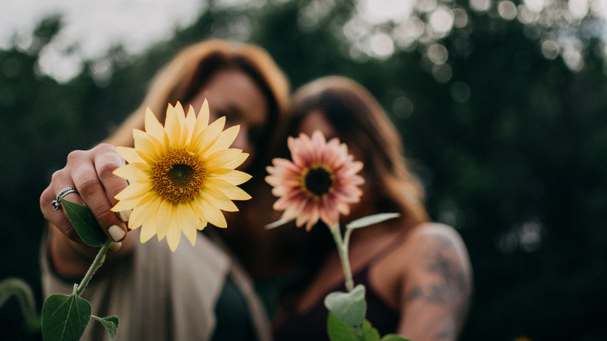 Due donne sorridenti che tengono dei fiori, simbolo di salute e benessere.