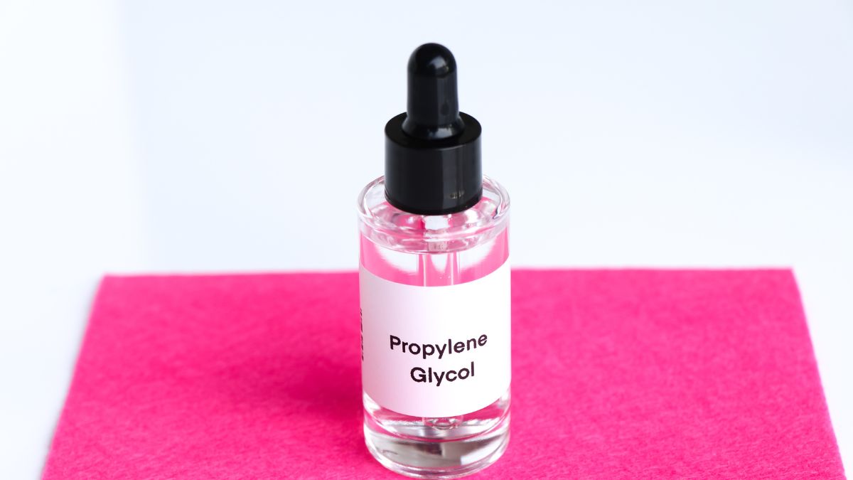 Flacone di glicole propilenico con etichetta su sfondo rosa.