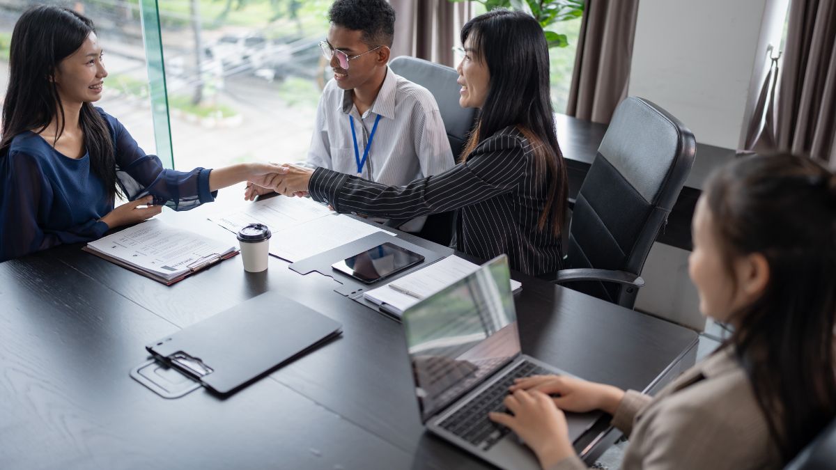 Due persone si stringono la mano durante un colloquio di lavoro in un ufficio moderno.