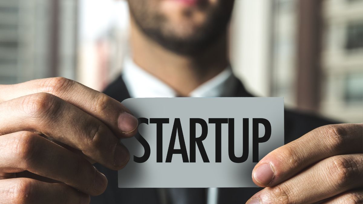 Un uomo in giacca tiene un biglietto con la scritta 'STARTUP'.